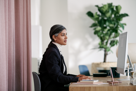 Vrouw staat met een laptop op het werk en lacht