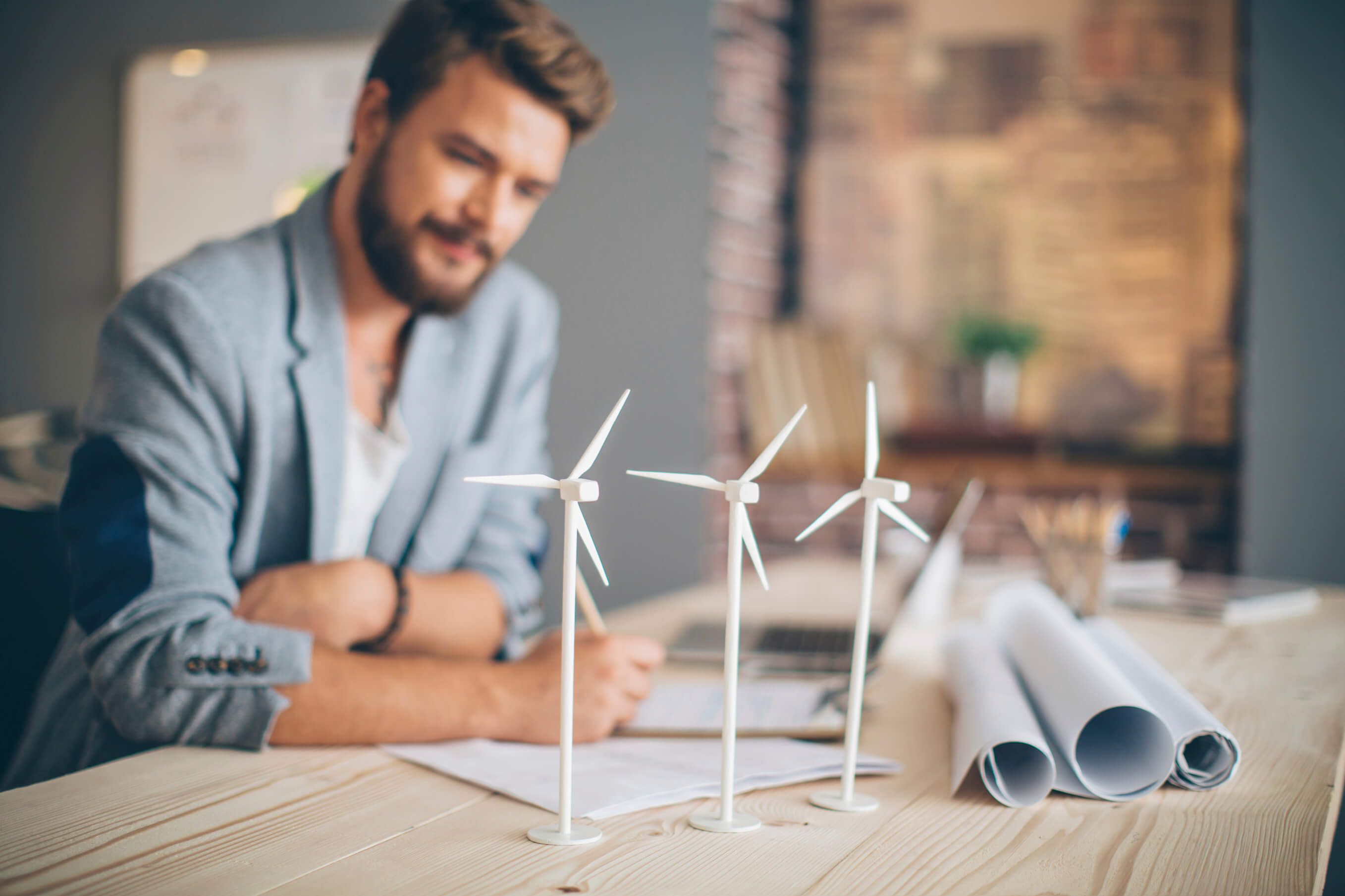 Jonge zakenman met 3 mini windmolens op bureau - Stroom