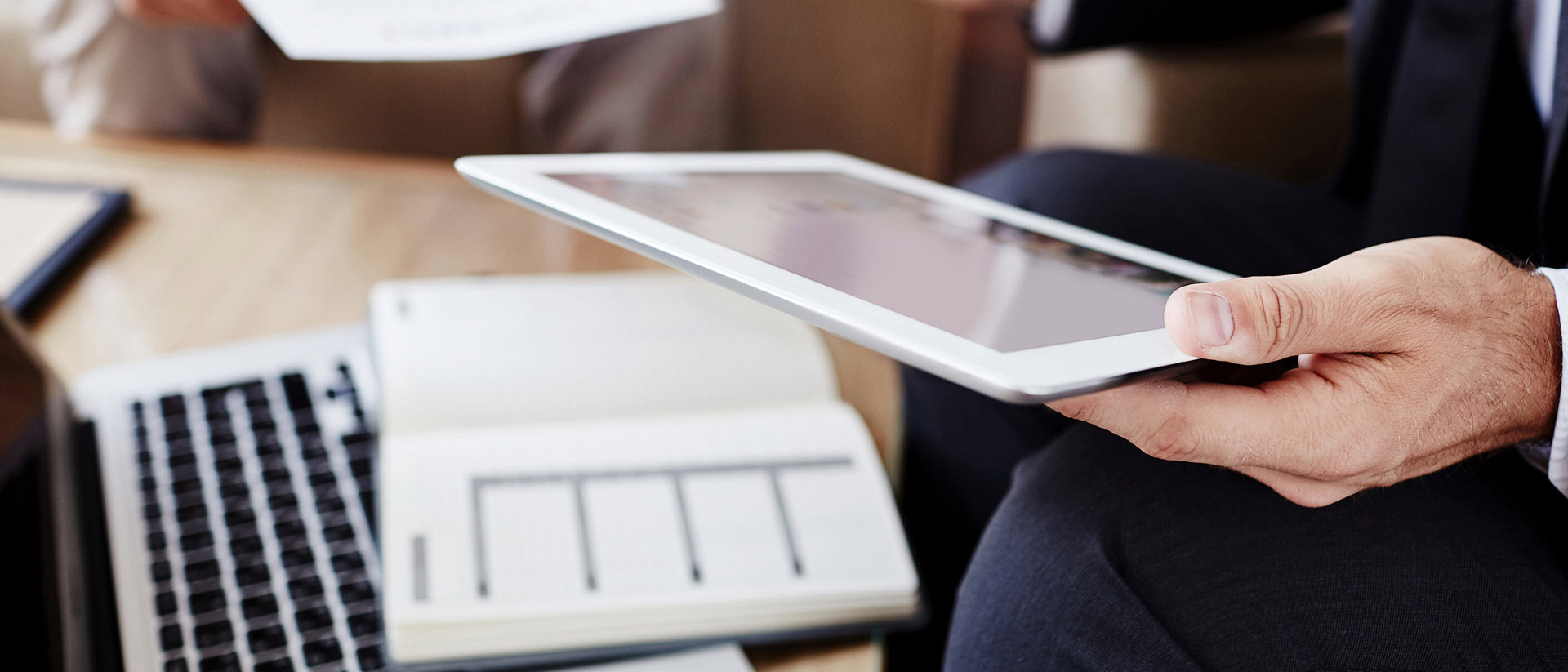 Man achter zijn laptop bekijk informatie over de specificatie van zijn jaarafrekening op de iPad