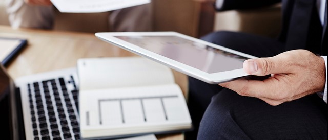 Close-up van man met tablet in zijn hand achter de laptop | Vattenfall Energie over de contractcheck: Zeker weten dat je goed zit