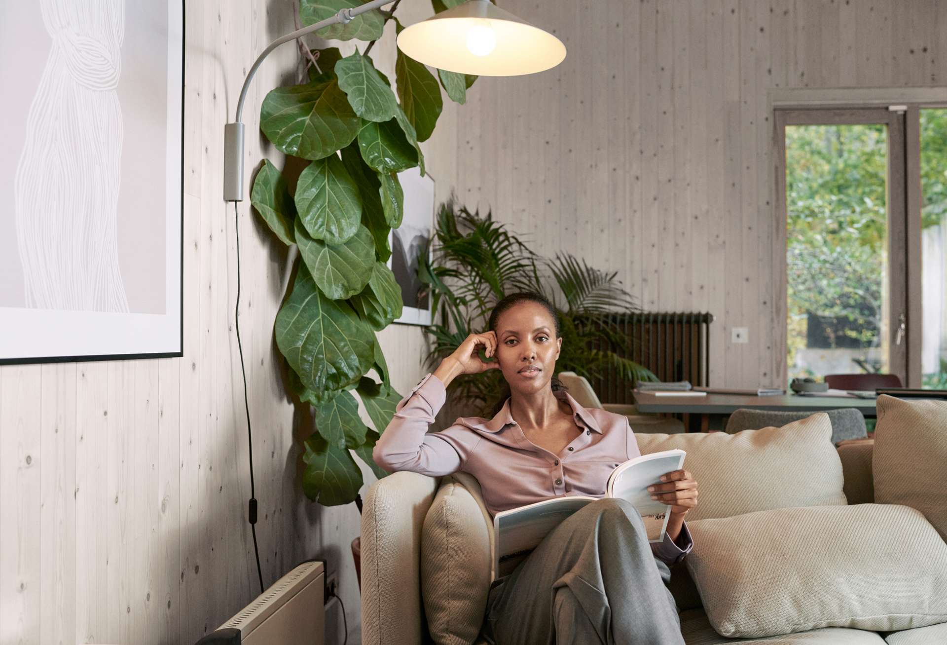 Mevrouw in huiskamer op bank met boek 