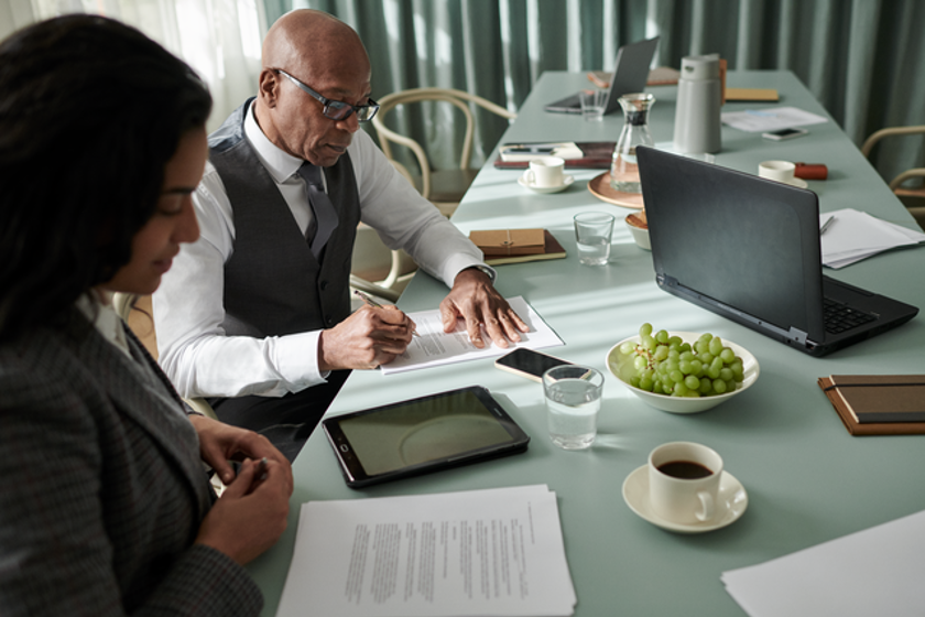 Een man en een vrouw zitten aan een bureau en ondertekenen een contract