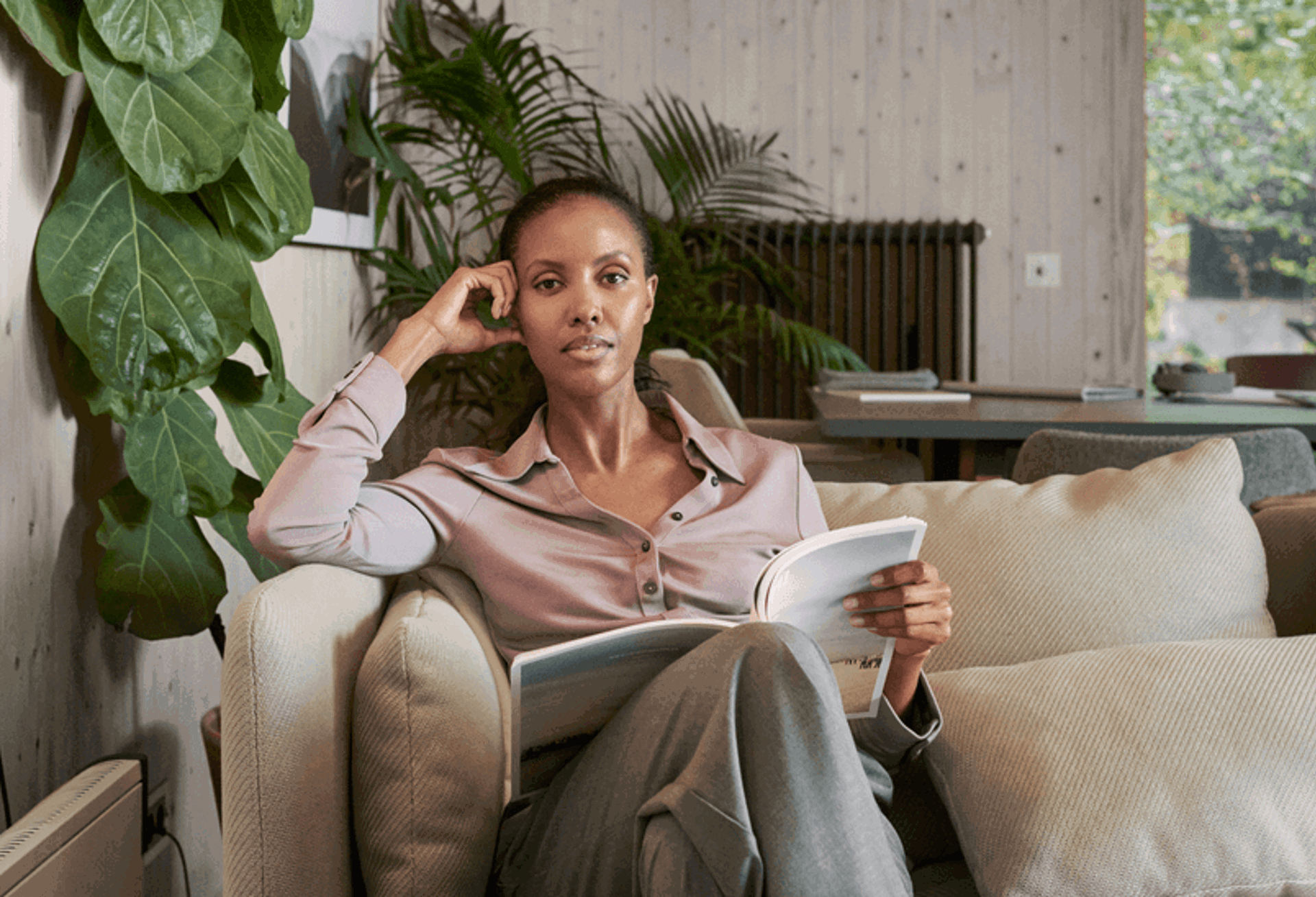 Mevrouw in huiskamer op bank met boek