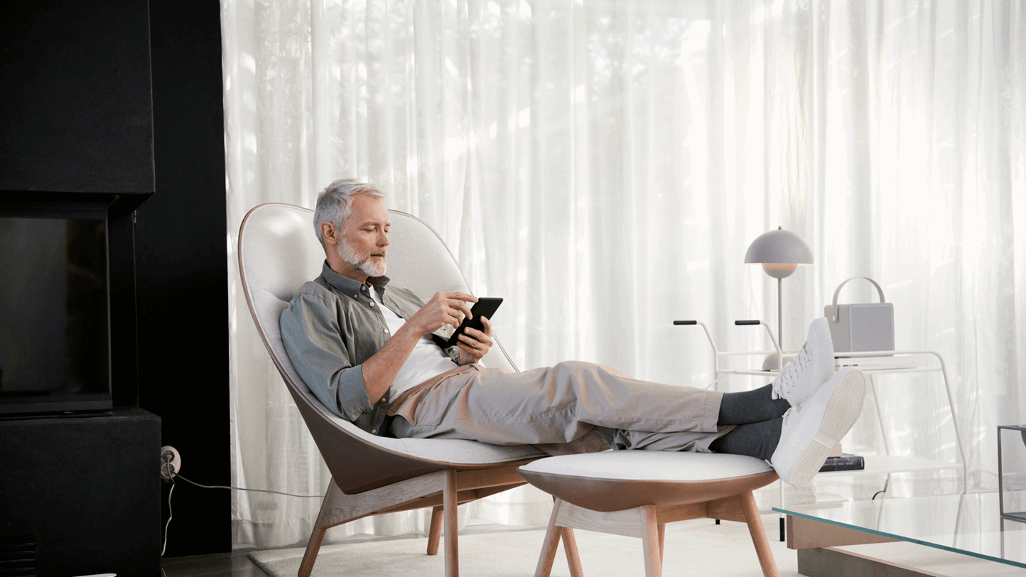 Man zit relaxed in zijn woonkamer op zijn tablet te kijken naar de gedaalde warmtetarieven