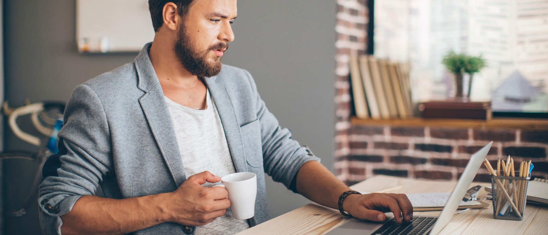 Ondernemer zit ontspannen achter zijn laptop met een kop koffie | Overweeg je om je energiecontract op te zeggen?