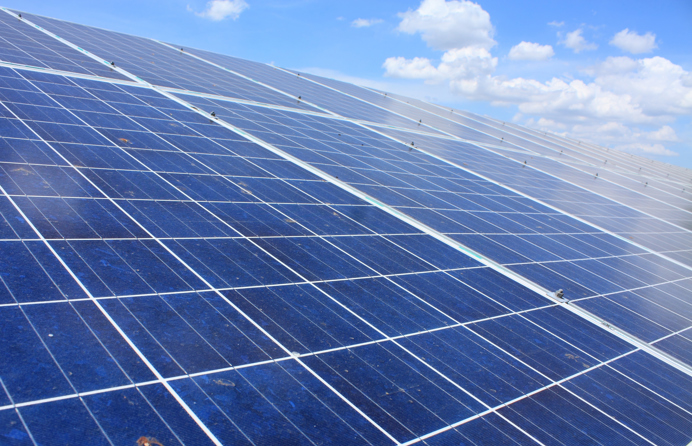 Acht grote zonnepanelen in de zon met blauwe lucht en paar wolken