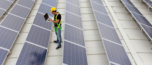 Installateur op dak van een bedrijfspand met veel zonnepanelen | Fiscaal voordeel op je zonnepanelen