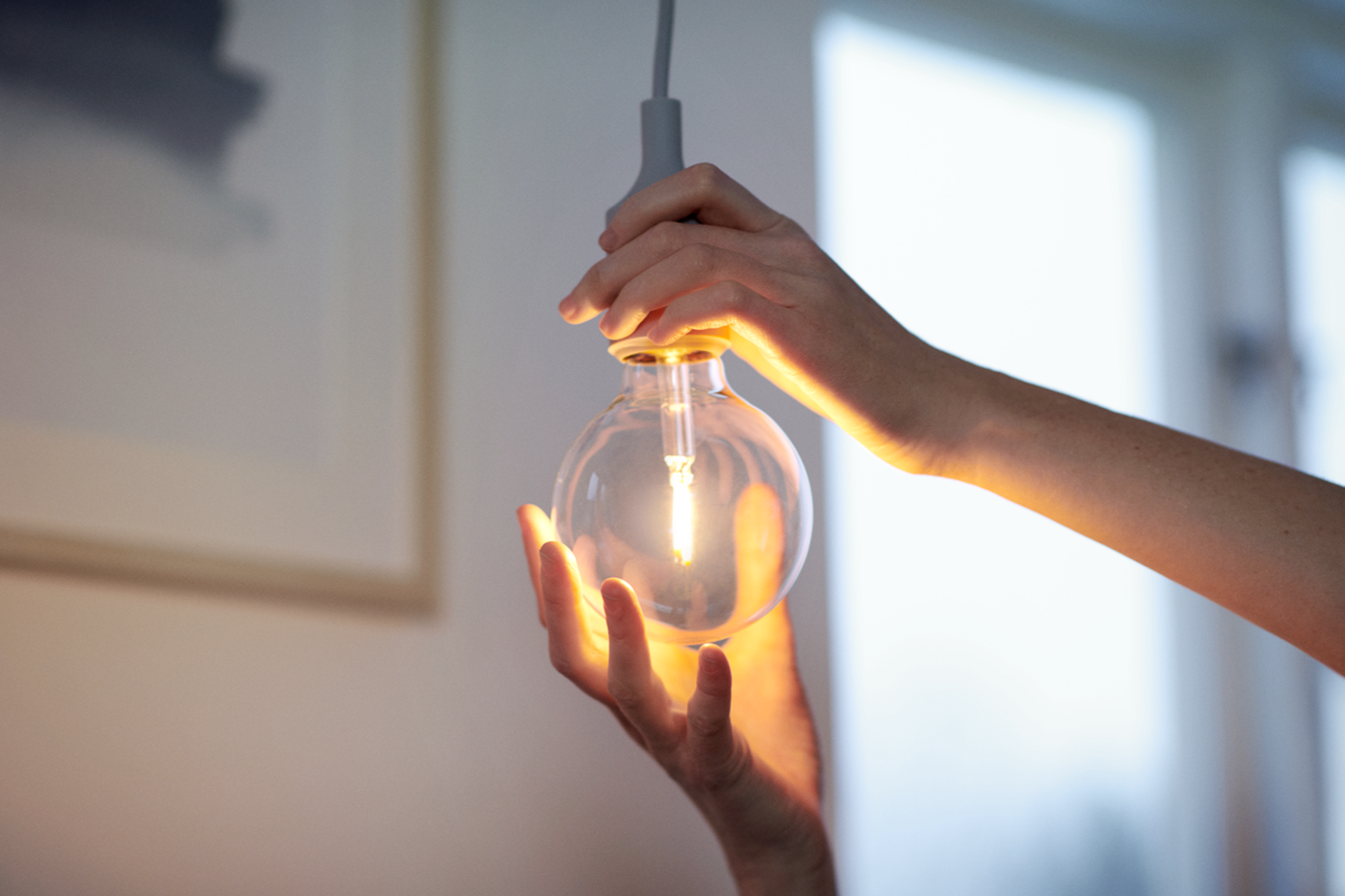 Closeup van handen die een lamp indraaien voor energie besparen met duurzame ledverlichting